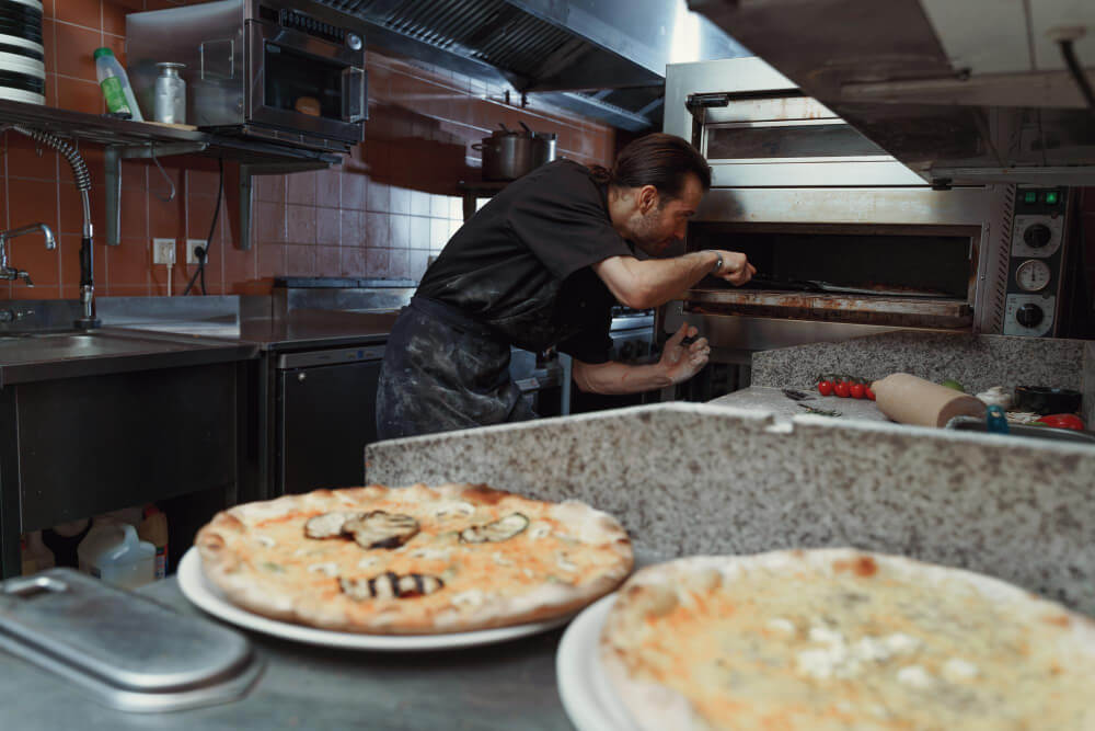 Pizza chef taking pizzas out of the oven